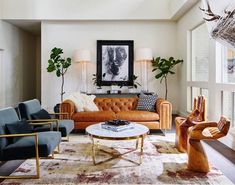 a living room filled with lots of furniture next to a painting on the wall above a coffee table