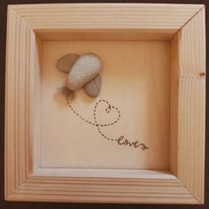 a rock in a wooden frame with the word love written on it and a heart