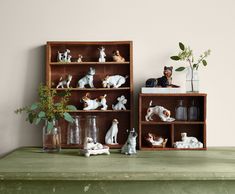 two wooden shelves filled with figurines and vases on top of a green table