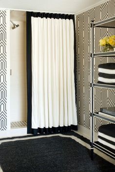 a bathroom with black and white decor on the walls, shower curtain, towel rack and rug