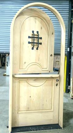 a wooden door with an arched top in a warehouse area next to other woodworking equipment