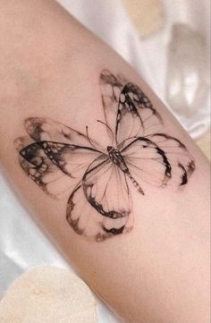 a woman's arm with a black and white butterfly tattoo on the left forearm