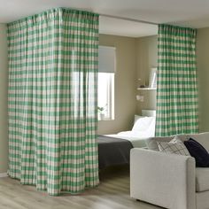 a green and white checkered curtain in a living room with a bed behind it