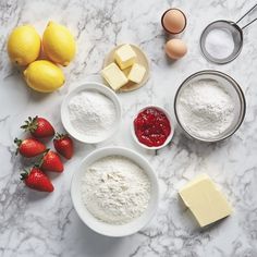 ingredients to make strawberry shortcakes laid out on a marble counter with lemons and butter