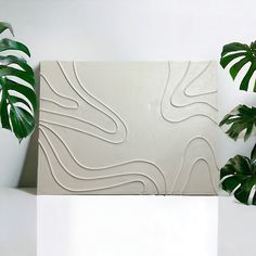 there is a plant next to a white wall with wavy lines on it and a green plant in the foreground