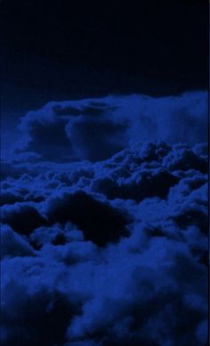 the night sky is full of clouds and dark blue hues as seen from an airplane window