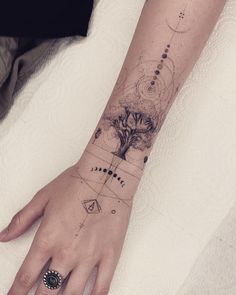 a woman's hand with a tree and compass tattoo on her left wrist,