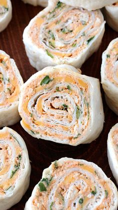 rolls with cheese and spinach on top sitting on a wooden table next to other rolls