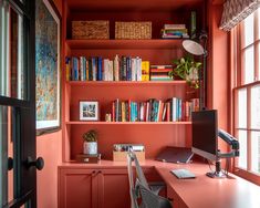 a home office with orange walls and bookshelves