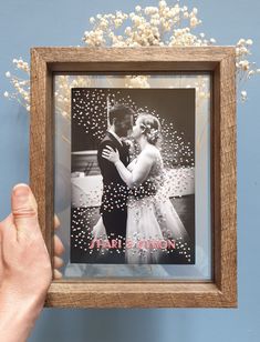 a person holding up a framed photo with confetti on it