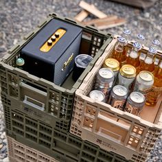 an open crate filled with beer bottles and other drinks on top of a gravel ground