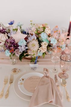 the table is set with pink and blue flowers