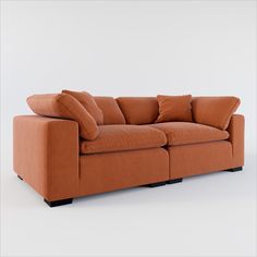 an orange couch with two pillows on it's back and one arm facing the camera