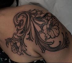 the back of a woman's shoulder with flowers and swirls tattoo on it