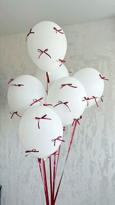 white balloons with red string tied to them in a vase on a table next to a wall