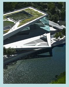 an aerial view of a building with grass on the roof and water in the foreground