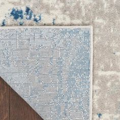 a blue and white area rug on top of a wooden floor next to a wood floor