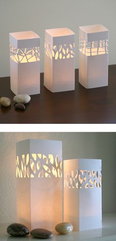 three white paper lanterns sitting on top of a table next to rocks and pebbles in front of them