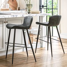 two chairs sitting on top of a wooden floor in front of a counter with flowers