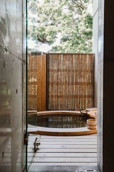 an outdoor hot tub in the middle of a wooden decked area with bamboo fence