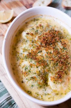 a white bowl filled with broccoli soup on top of a wooden cutting board