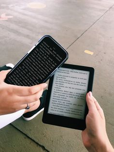 two hands are holding an electronic device and touching it's screen on the sidewalk