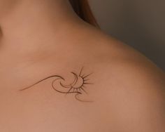 the back of a woman's shoulder with a sun and wave tattoo on it