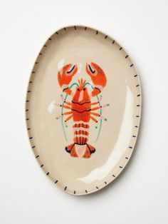 a ceramic plate with a lobster painted on it's front and back sides, sitting on a white surface