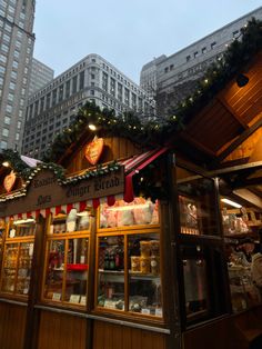 an outdoor market with christmas decorations and lights on the roof, in front of tall buildings