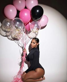 a woman is kneeling down with balloons in front of her and posing for the camera