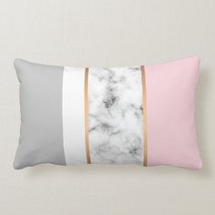 a white and pink marble pillow with gold stripes on the front, along with a black and grey stripe down the middle