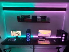 a computer desk with two monitors and speakers on top of it in front of a purple light