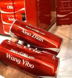 two cans of coca - cola sitting on top of each other in a store aisle