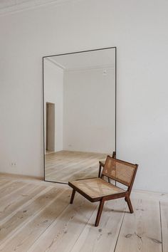 a chair sitting on top of a wooden floor next to a large mirror in a room