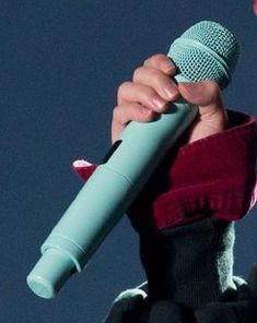 a close up of a person holding a microphone in front of a blue sky background