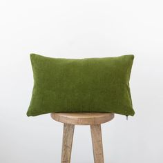 a green pillow sitting on top of a wooden stool