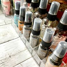 many different types of spray bottles in a clear container on a wooden table next to each other