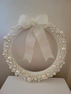 a white wreath decorated with pearls and a bow