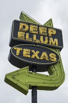 a neon sign for deep elum texas with an arrow pointing to the left and right