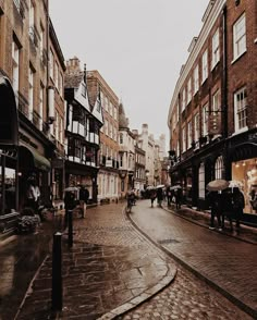 people walking down the street with umbrellas on a rainy day in an old european city