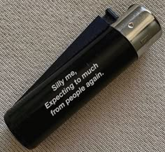 a black lighter with a message on it sitting on a carpeted floor next to a wall