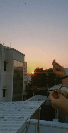 someone is flying a kite on top of a roof in the city at sunset or dawn