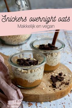 three small jars filled with desserts on top of a wooden cutting board next to a pink napkin