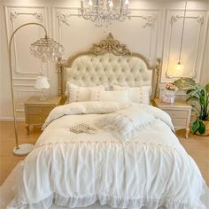 a large white bed sitting inside of a bedroom next to a chandelier above it