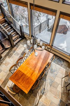 an aerial view of a dining room table and chairs in front of large windows overlooking the snow covered mountains