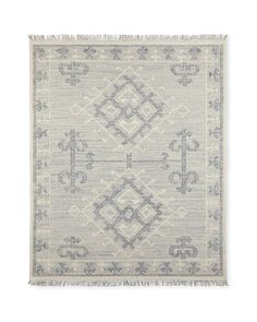 a gray and white rug with fringes on the bottom, in front of a white background