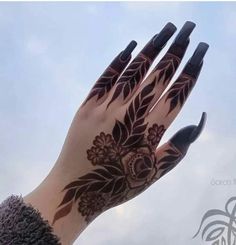 a woman's hand with black and white tattoos on it, against a blue sky