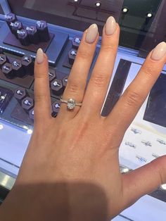 a woman's hand with a ring on it next to a display of jewelry