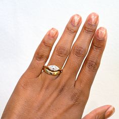 a woman's hand with a gold and white ring on top of her finger