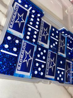 six blue and white stickers with stars on them in a plastic container next to a marble counter top